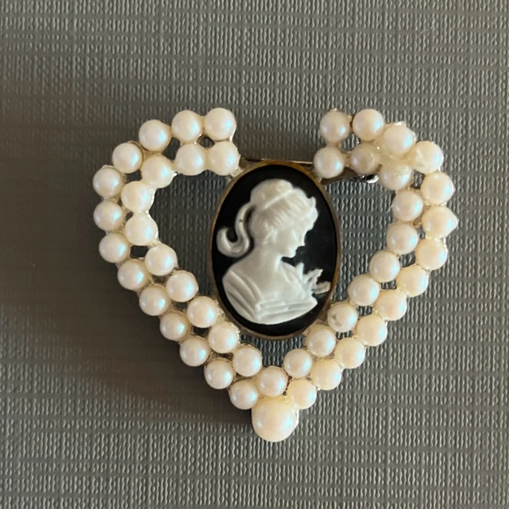 Vintage heart-shaped brooch featuring a black and white cameo with faux pearls.